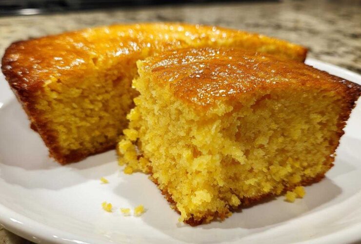 Close-up of a moist, golden slice of sourdough cornbread with a shiny, glazed top.