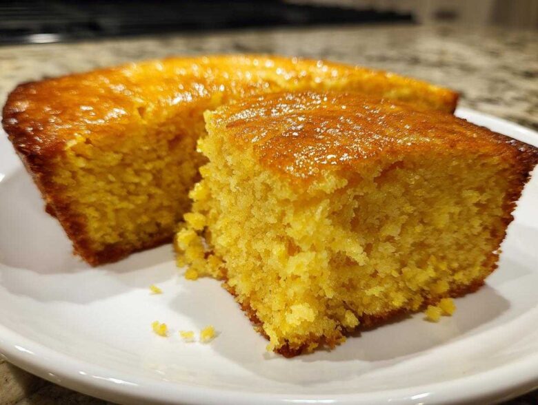 Close-up of a moist, golden slice of sourdough cornbread with a shiny, glazed top.