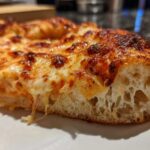 A close-up cross-section showing the airy crumb structure of a pizza made with sourdough discard pizza dough.