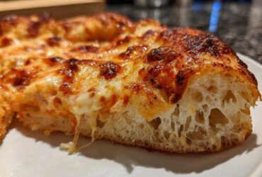 A close-up cross-section showing the airy crumb structure of a pizza made with sourdough discard pizza dough.