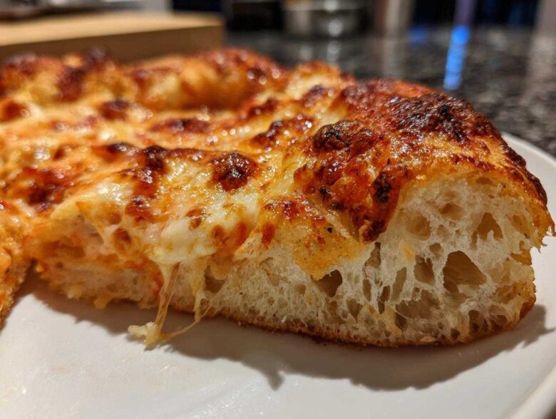 A close-up cross-section showing the airy crumb structure of a pizza made with sourdough discard pizza dough.