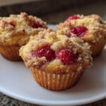 Three delicious strawberry muffins topped with a sugary crumble, resting on a white plate.