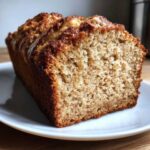 Close-up of a moist slice of sugar free banana bread showing a golden-brown crust and soft crumb.