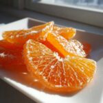 Close-up of bright orange candied orange slices heavily coated in sparkling sugar crystals.