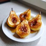 Four halves of golden baked pears topped with a glistening brown sugar and cinnamon mixture.