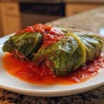 Two savory cabbage rolls filled with meat, covered in rich tomato sauce, served on a white plate.