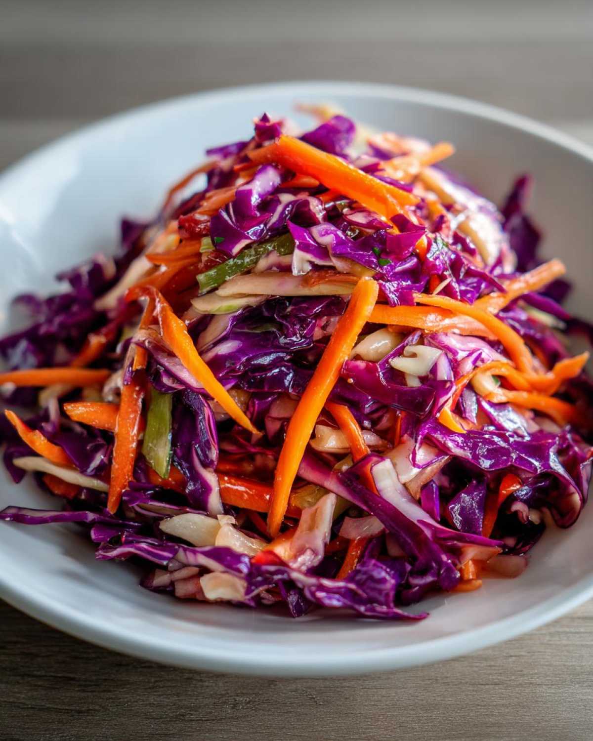 Close-up of a vibrant red cabbage salad mixed with bright orange shredded carrots in a white bowl.