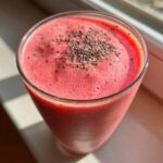 Close-up of a vibrant pink watermelon smoothie in a glass, topped generously with chia seeds.