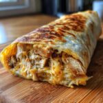 Close-up of a crispy Air Fryer Crispy Chicken Bacon Ranch Wrap, showing shredded chicken and melted cheese filling.