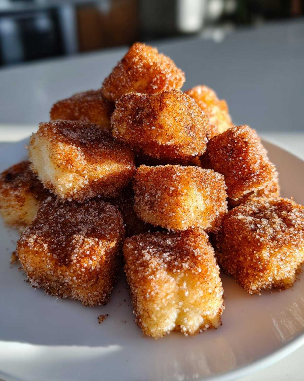 A close-up shot of a pile of Air Fryer Crispy Cinnamon Sugar Biscuit Bites coated heavily in cinnamon sugar.