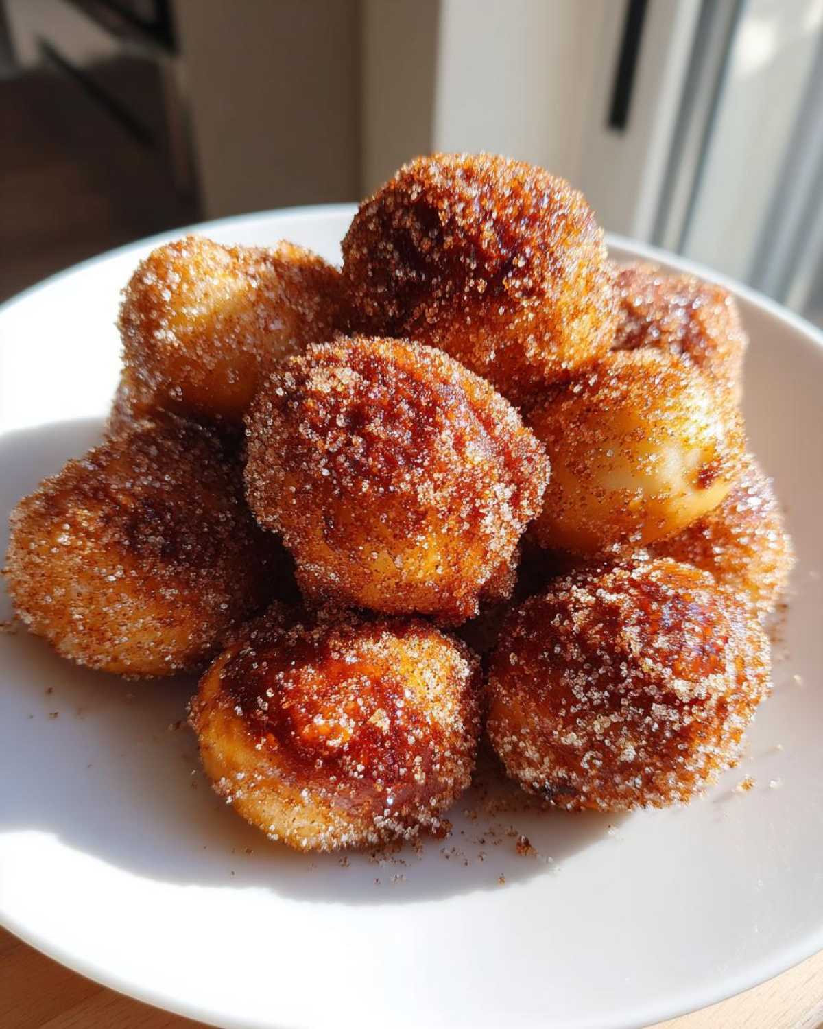 A close-up of several Air Fryer Crispy Cinnamon Sugar Pretzel Bites piled high on a white plate.