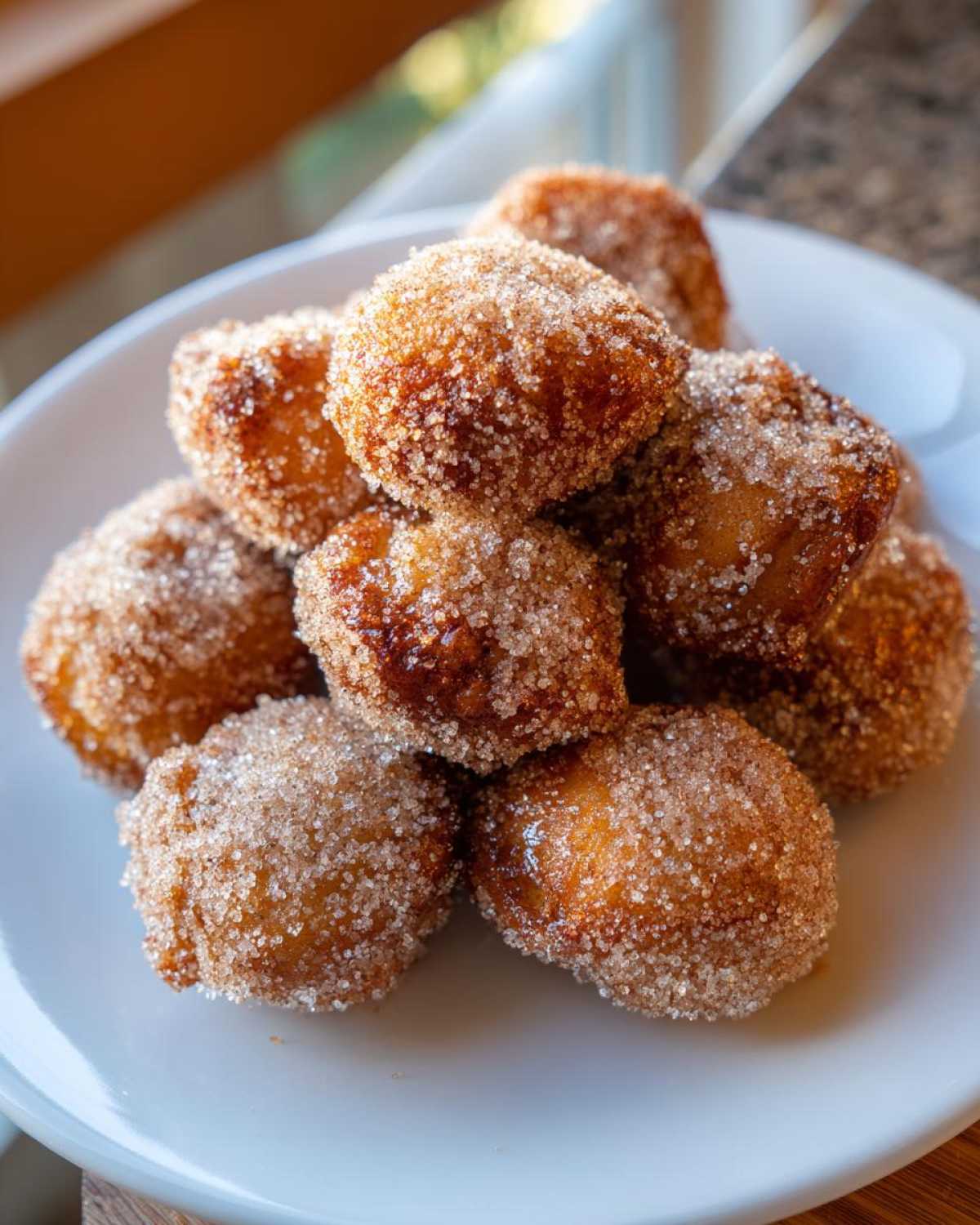 A close-up stack of golden brown Air Fryer Crispy Cinnamon Sugar Pretzel Bites coated heavily in sparkling cinnamon sugar.