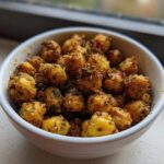 A white bowl filled with golden brown Air Fryer Crispy Garlic Herb Chickpeas coated in seasoning.