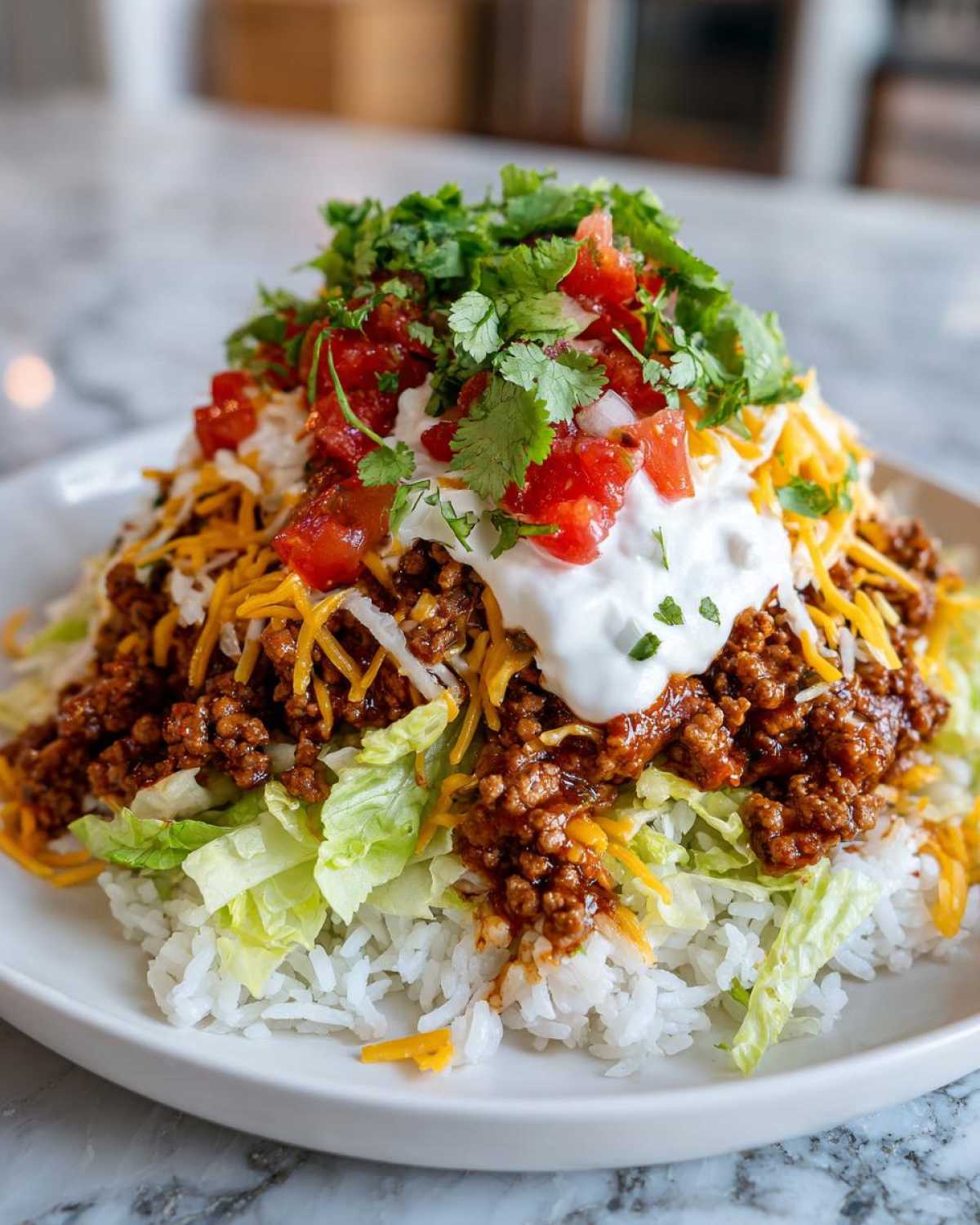 A close-up of a serving of Air Fryer Crispy Turkey Taco Bowls featuring seasoned ground turkey over rice, lettuce, cheese, sour cream, and cilantro.