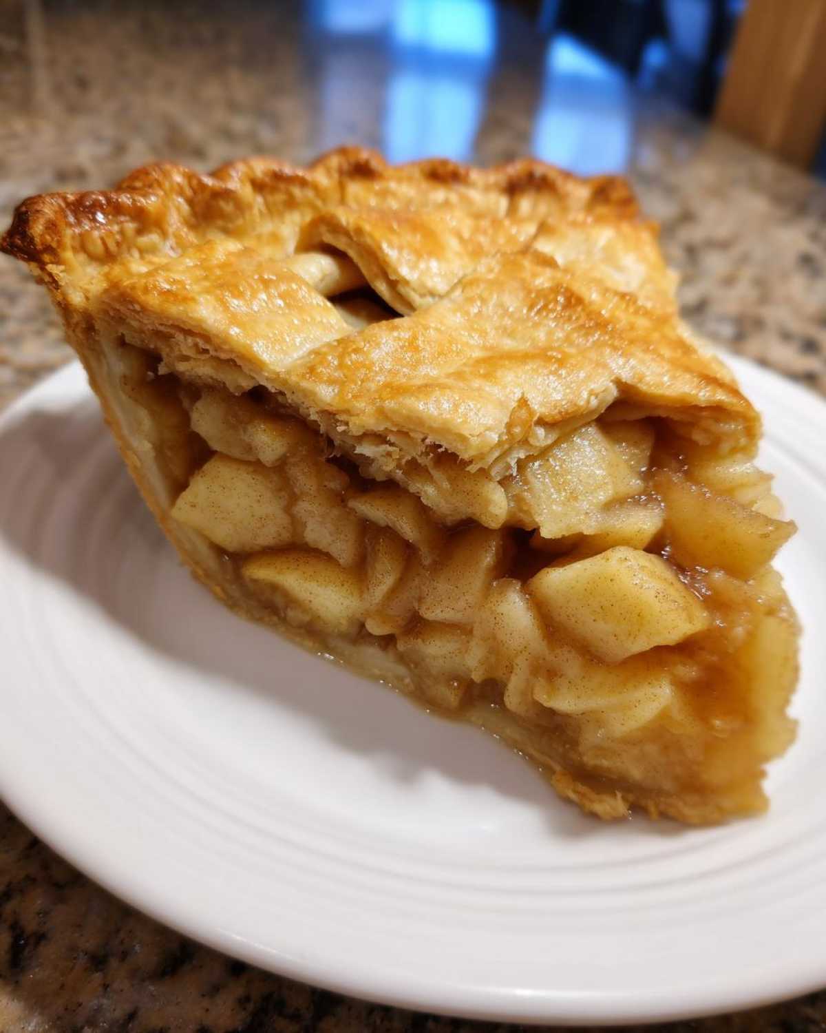 Close-up of a thick slice of apple pies showing chunky, spiced filling and a golden, flaky lattice crust.