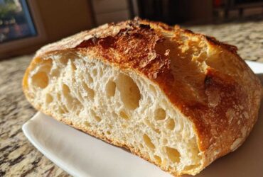 Cross-section of artisan bread showing an open, airy crumb structure and a deeply browned, crisp crust.