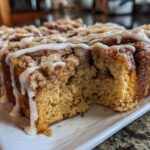 Close-up of Banana Bread Batter Cinnamon Buns loaf with a section removed, showing crumb texture and white icing drizzle.