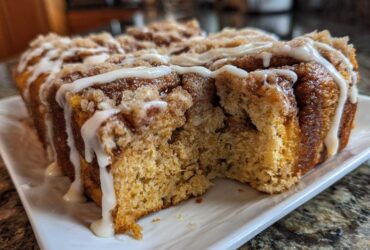 Close-up of Banana Bread Batter Cinnamon Buns loaf with a section removed, showing crumb texture and white icing drizzle.
