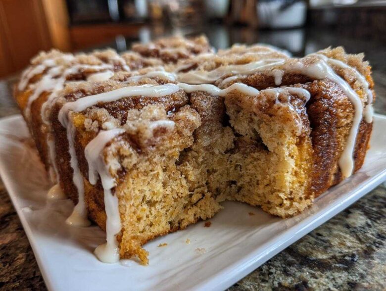 Close-up of Banana Bread Batter Cinnamon Buns loaf with a section removed, showing crumb texture and white icing drizzle.