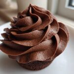 Close-up of a cupcake topped with rich, dark chocolate buttercream frosting piped in a beautiful swirl.