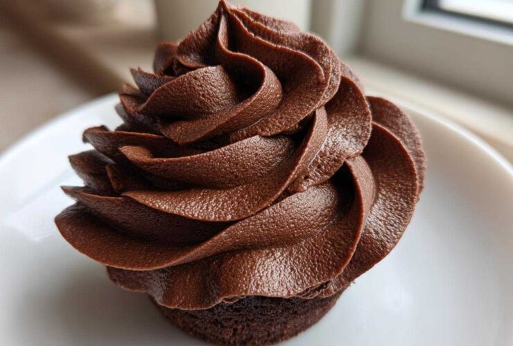 Close-up of a cupcake topped with rich, dark chocolate buttercream frosting piped in a beautiful swirl.
