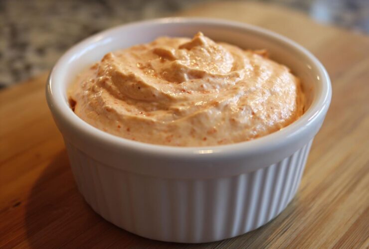 A close-up of creamy, orange-hued Copycat Classic Burger Spread Sauce swirled in a small white ramekin.