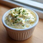 A creamy serving of Copycat Pizza Garlic Parmesan Dip Sauce topped with shredded cheese and fresh parsley.