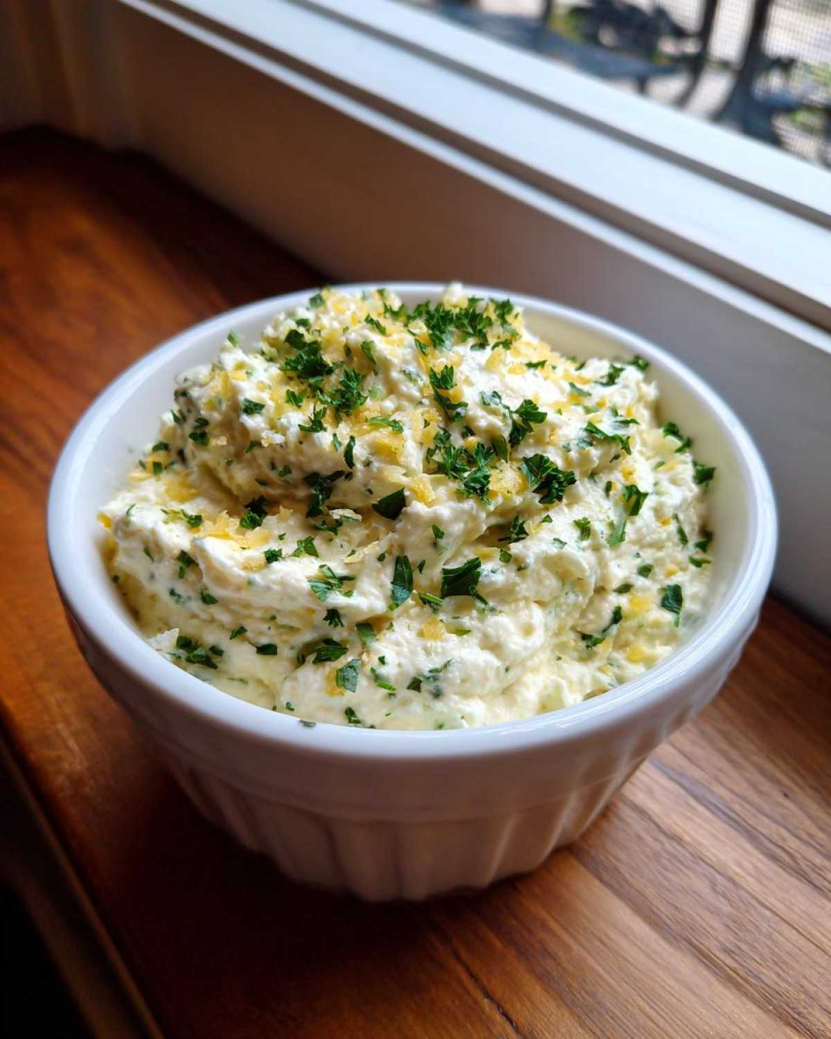 A creamy bowl of Copycat Pizza Garlic Parmesan Dip Sauce topped with fresh parsley and parmesan zest.