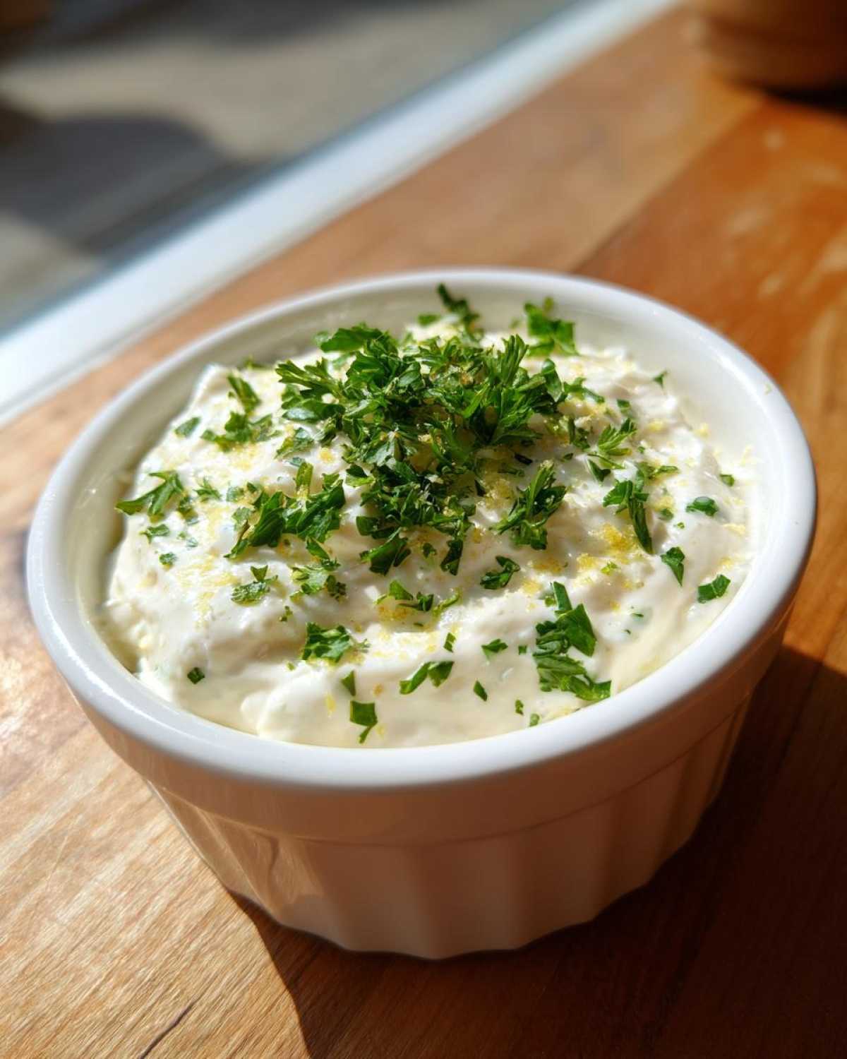 Close-up of rich Copycat Pizza Garlic Parmesan Dip Sauce topped with fresh parsley and lemon zest.