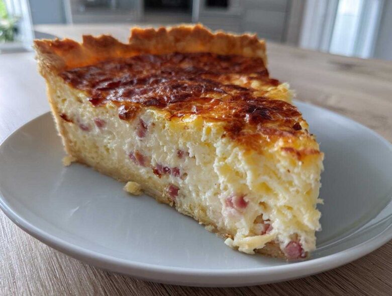 A thick slice of Cottage Cheese Quiche with visible ham pieces, resting on a white plate.