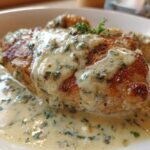 A perfectly seared chicken breast smothered in a rich, creamy Asiago chicken sauce flecked with green herbs.