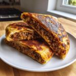 Three halves of Crispy Lebanese Arayes Juicy Beef Pita Pockets stacked on a white plate, showing the savory ground meat filling.