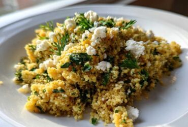 A close-up of Easy One-Pot Creamy Lemon Herb Couscous topped with crumbled feta cheese and fresh parsley.