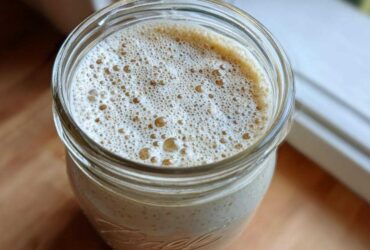Overhead view of creamy chia seed pudding topped with a layer of light brown foam in a glass Ball jar.