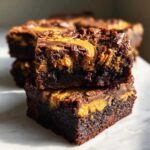 Two stacked squares of rich Gluten-Free Chocolate Peanut Butter Swirl Brownies showing the dense texture and peanut butter swirl.