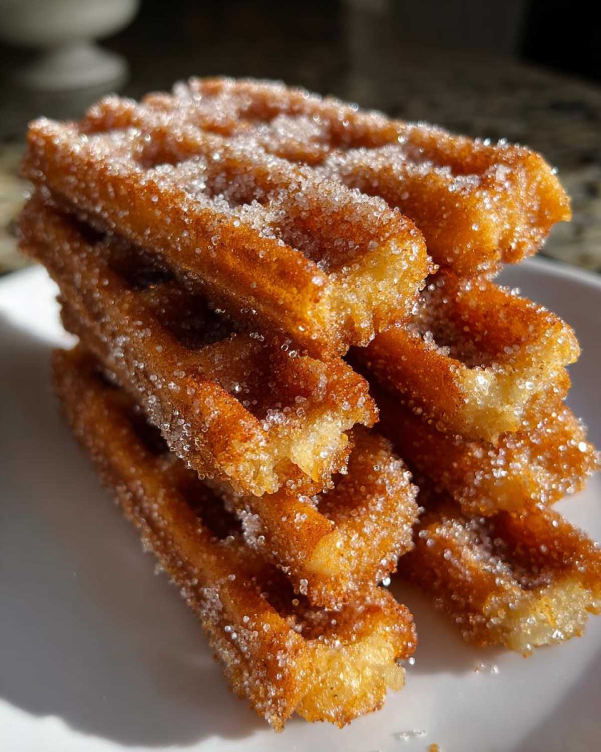 A close-up stack of crispy, golden Gluten-Free Cinnamon Sugar Waffle Sticks heavily coated in sparkling sugar.