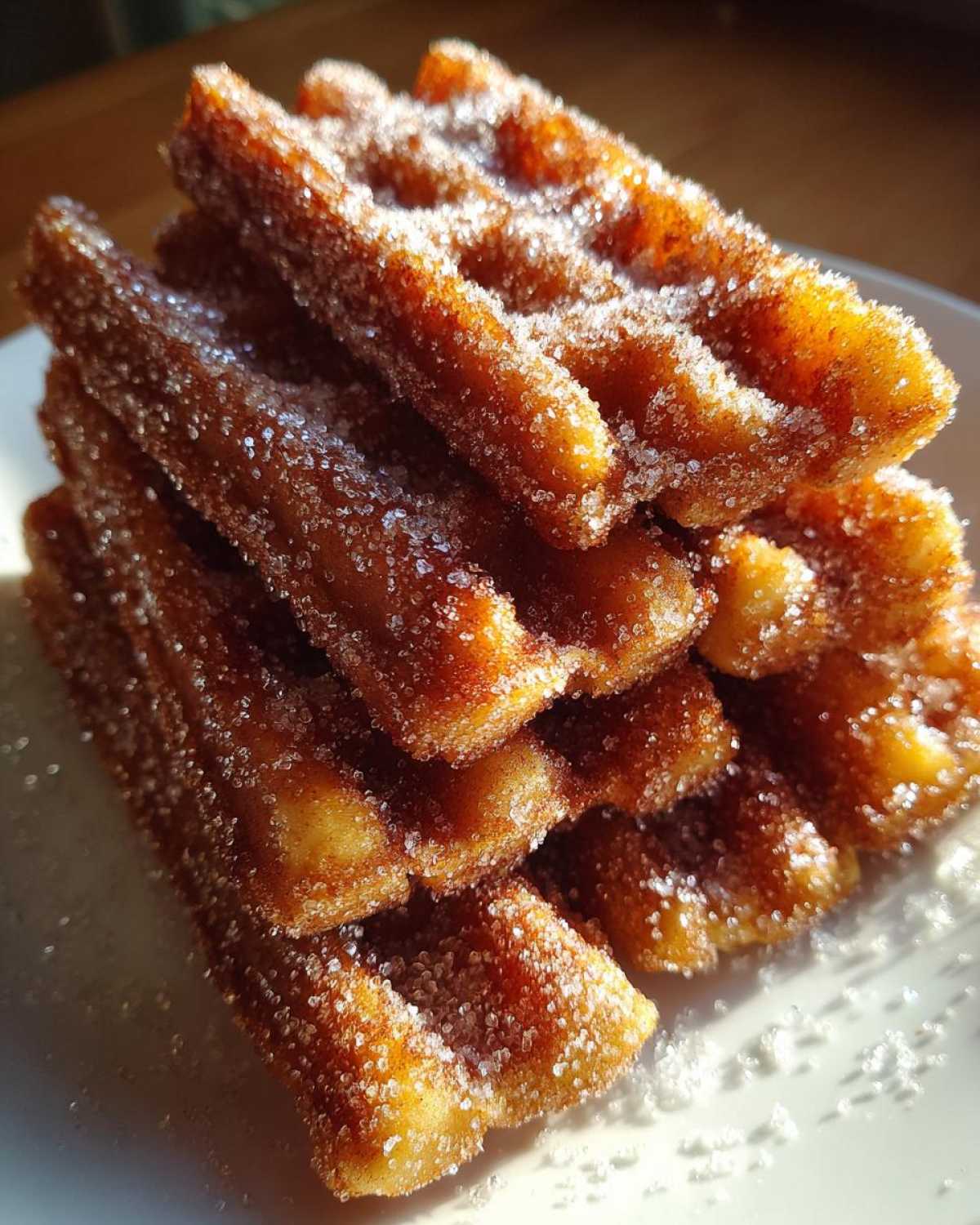 A close-up stack of golden brown Gluten-Free Cinnamon Sugar Waffle Sticks heavily coated in sparkling sugar.