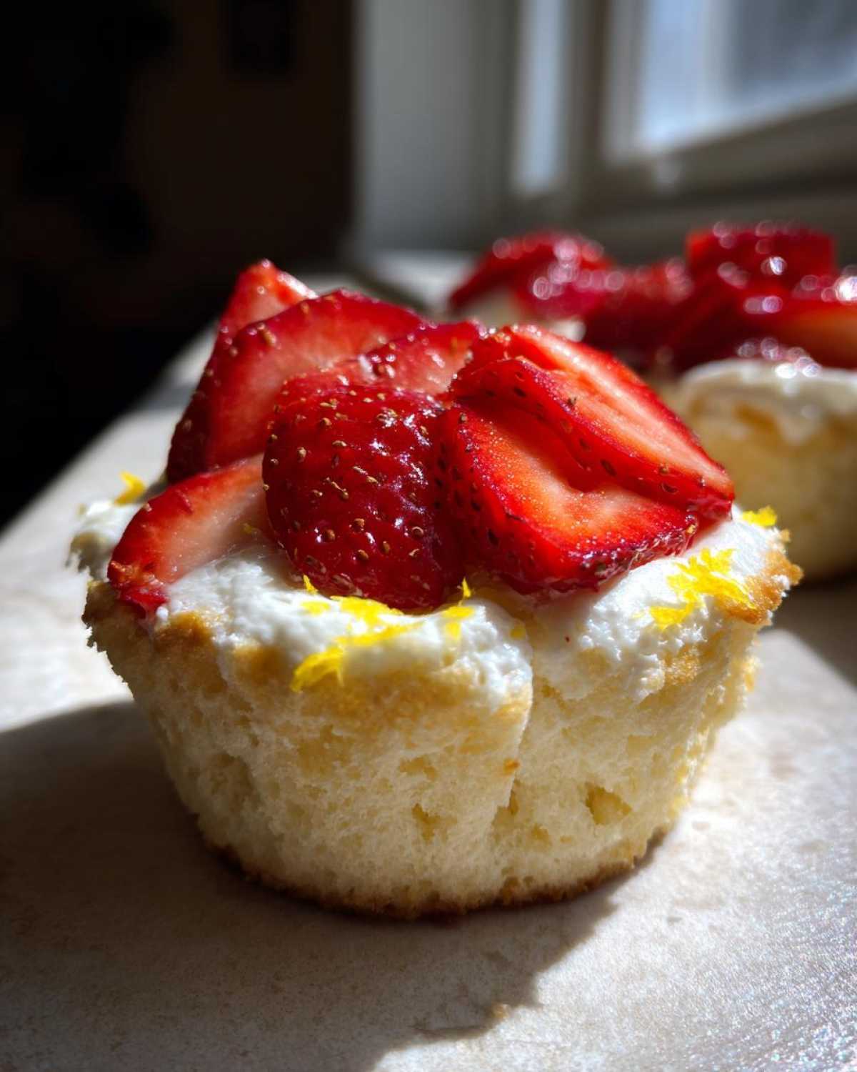 Close-up of a Gluten-Free Lemon Strawberry Angel Food Cup topped with whipped cream and fresh sliced strawberries.