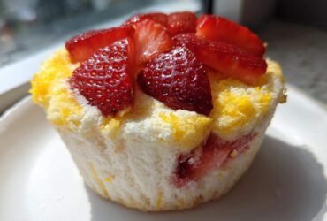 A single Gluten-Free Lemon Strawberry Angel Food Cup topped with fresh sliced strawberries, sitting on a white plate.