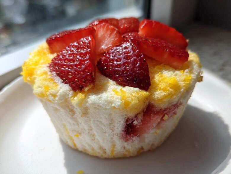 A single Gluten-Free Lemon Strawberry Angel Food Cup topped with fresh sliced strawberries, sitting on a white plate.
