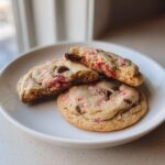 Three Gluten-Free Strawberry Chocolate Chip Cookies on a white plate, one broken open to show the soft interior.