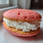 Close-up of a single Gluten-Free Strawberry Lemon Whoopie Pie with pink cakes and thick white cream filling.