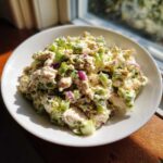 A bright, close-up serving of high protein chicken salad featuring chunks of chicken, green celery, and red onion in a creamy dressing.