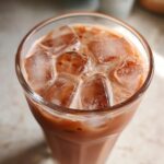 Close-up of a tall glass filled with Iced Raspberry Vanilla Chai and large ice cubes.