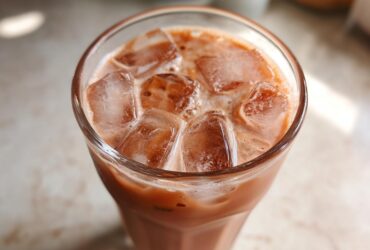 Close-up of a tall glass filled with Iced Raspberry Vanilla Chai and large ice cubes.