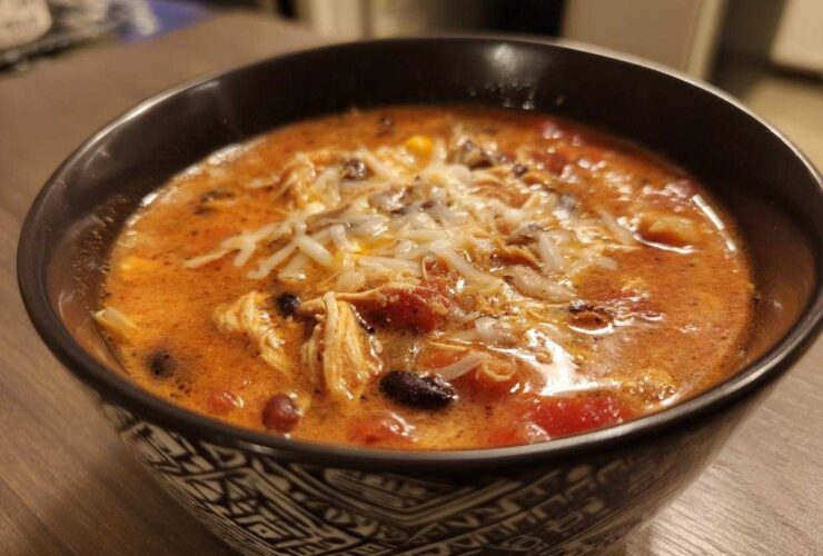 A close-up of a bowl of Instant Pot Creamy Chicken Enchilada Soup topped with shredded cheese.