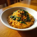 A close-up of Instant Pot Creamy Coconut Lentils with Spinach served in a white bowl on a wooden table.