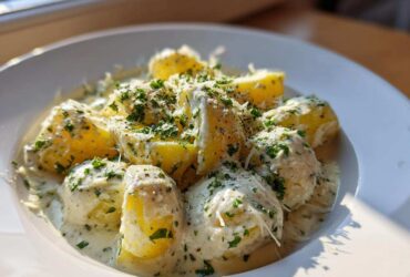 Close-up of Instant Pot Creamy Garlic Butter Potatoes covered in a rich sauce, topped with parsley and grated cheese.