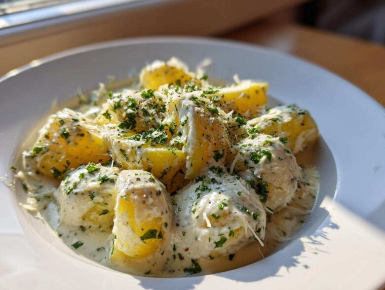 Close-up of Instant Pot Creamy Garlic Butter Potatoes covered in a rich sauce, topped with parsley and grated cheese.