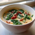 Close-up of a white bowl filled with Instant Pot Creamy Tuscan White Bean Soup, featuring white beans, spinach, and sun-dried tomatoes.